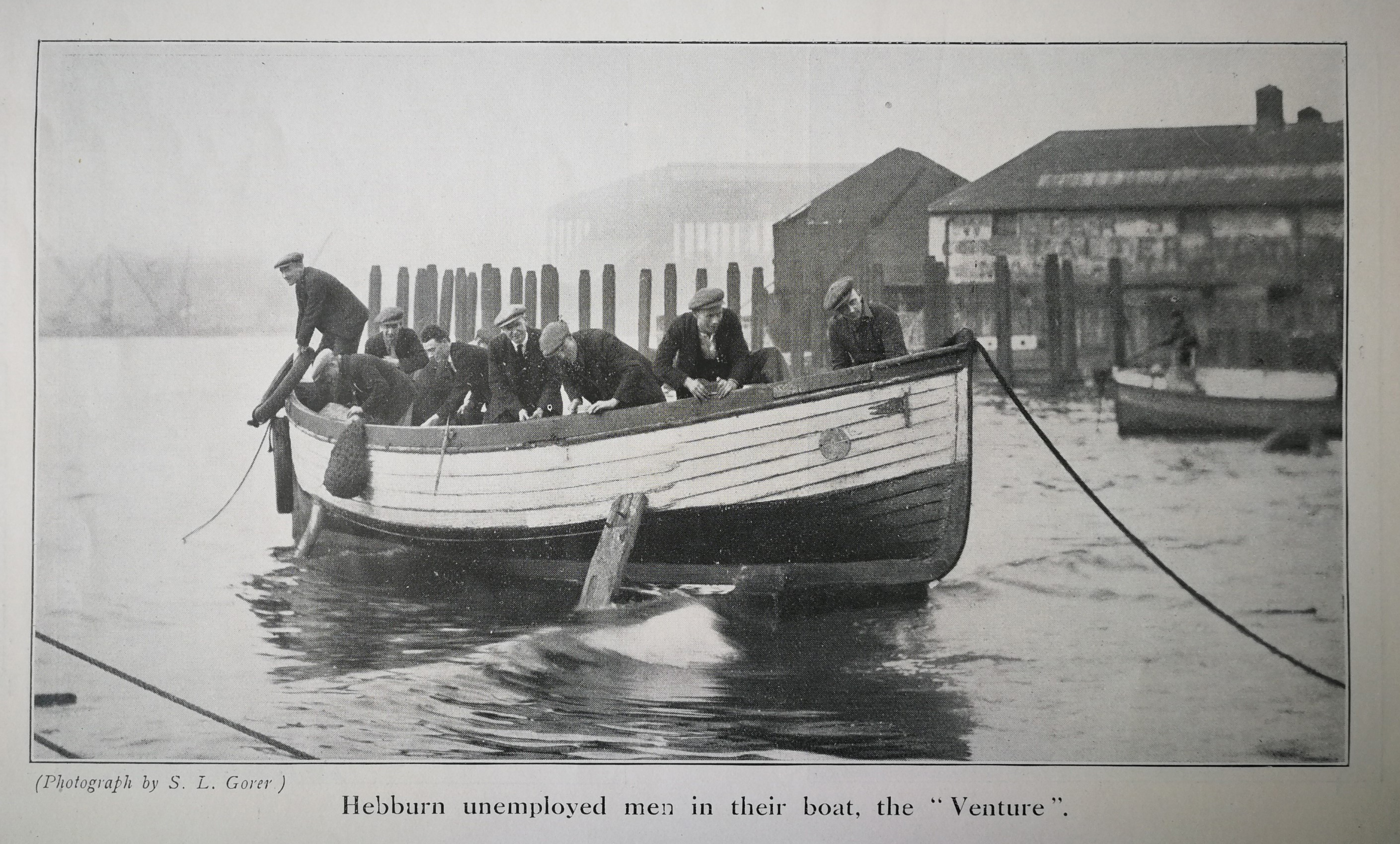 A group of men in flat caps stand in a small boat