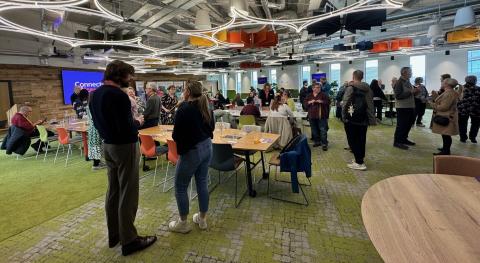 A large group of people in a meeting room chatting 
